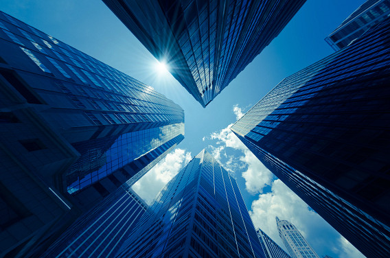 An upward view of skyscrapers against a sunny blue sky