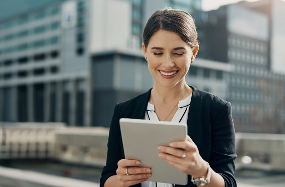 businessperson in city reading a tablet device