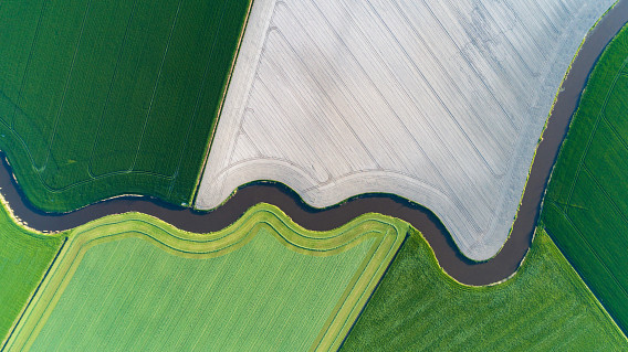 Aerial shot of curves and lines in a Dutch agricultural landscape. This natural waterway (Kromme Raken) flows through land which was cultivated centuries ago. The allotments changed several times since then but this little stream